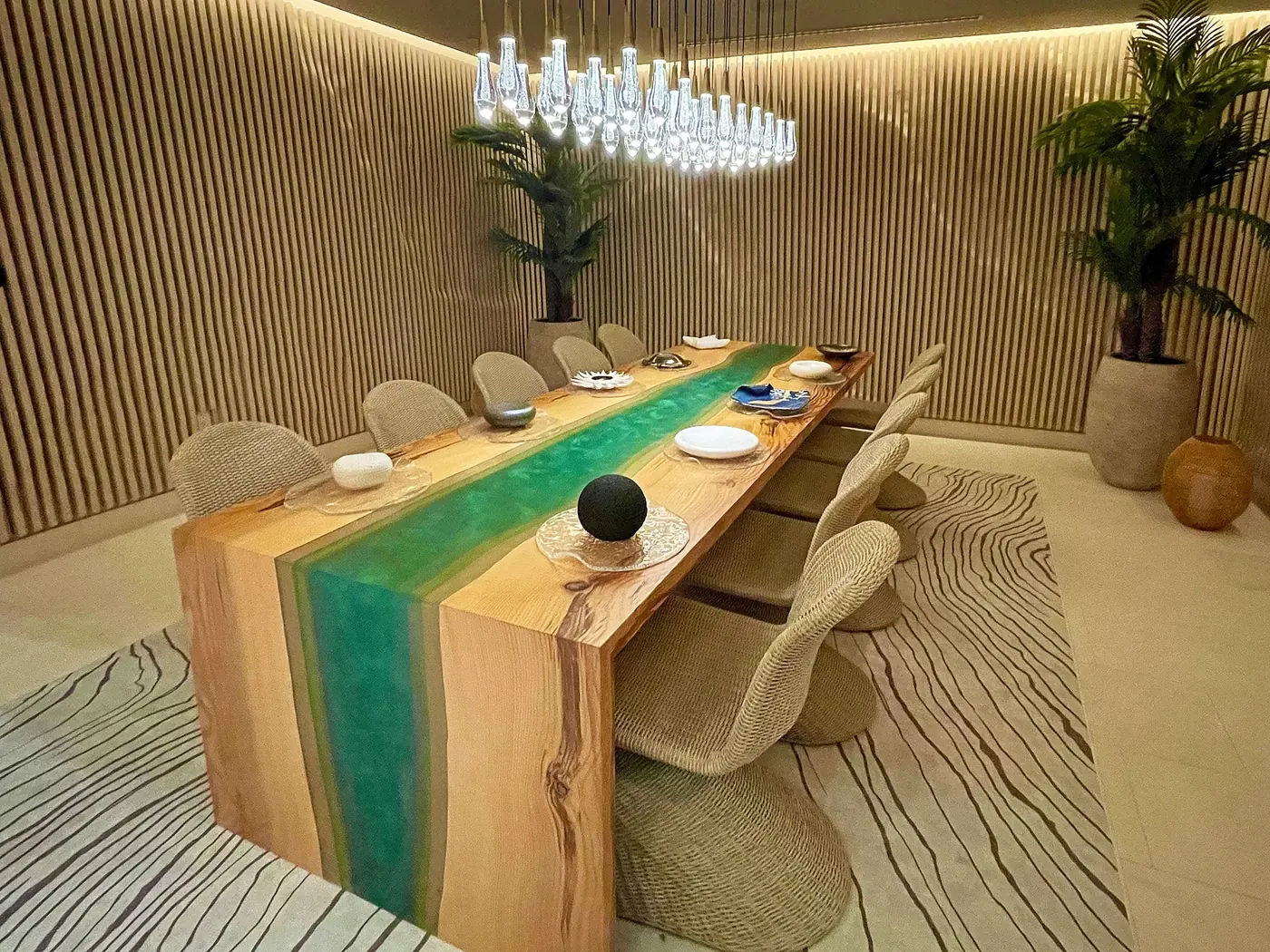The Chef’s Table at Mistura: a long wooden table with woven chairs under a cluster of glass pendant lights