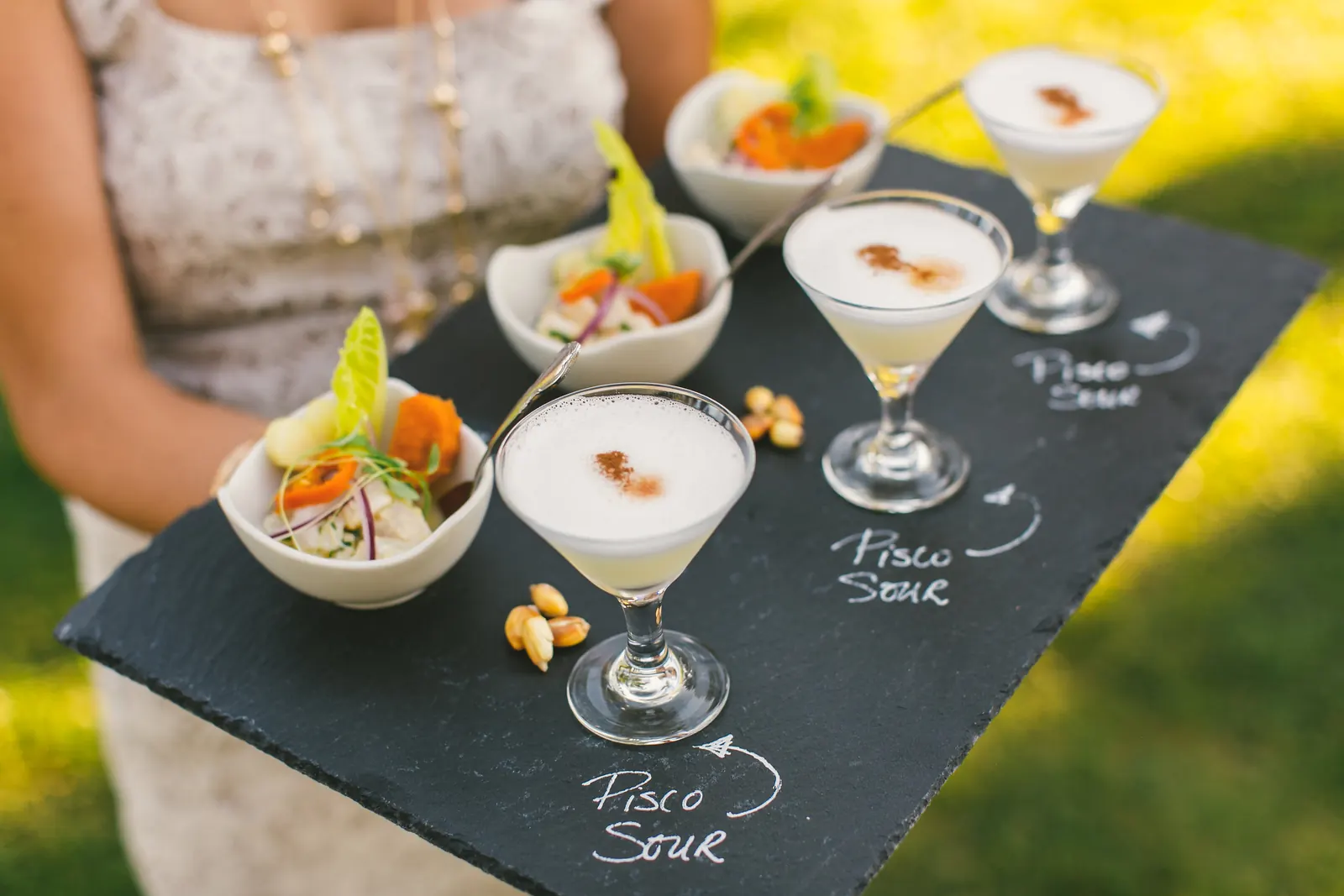 Pisco sours and ceviche cups on a slate tray, served by Mistura Catering at an outdoor event
