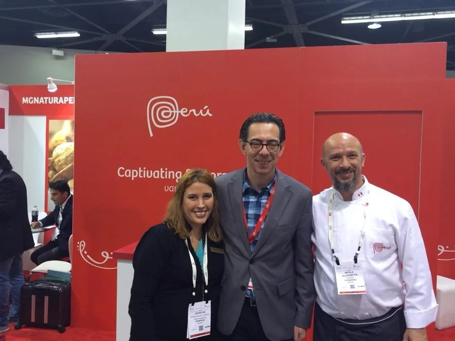 Chef Nicola in chef’s whites with two people at a red Perú booth at a trade show