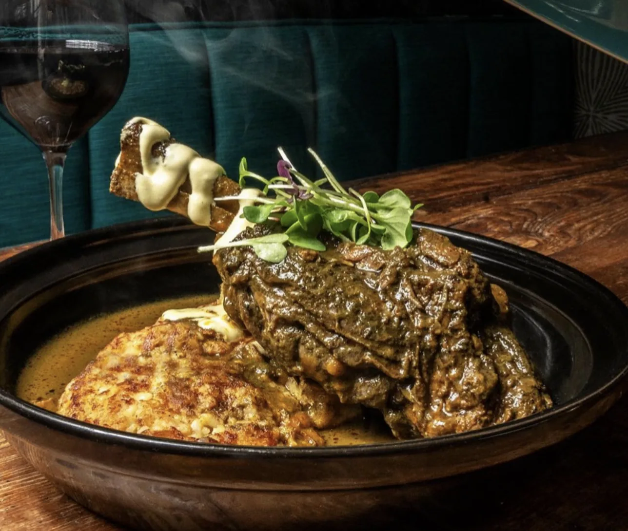 Seco de Cordero: a braised lamb shank in green cilantro sauce over a golden tacu tacu